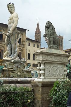 a man standing in front of a fountain with two statues on it's sides