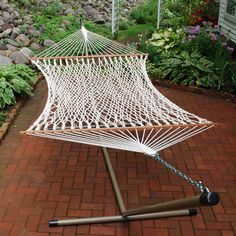 a white hammock sitting on top of a brick walkway