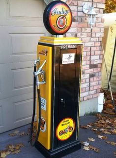 a yellow and black gas pump sitting in front of a garage