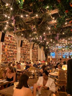 people sitting at tables in a restaurant with lots of books on the wall behind them