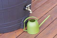 a green watering can sitting on top of a wooden floor