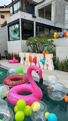 an inflatable flamingo float floating on top of a pool surrounded by balls