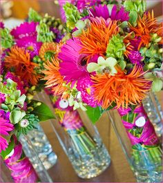 several vases filled with colorful flowers on top of a wooden table next to each other