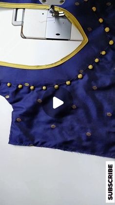 the sewing machine is working on an embroidered blue dress with gold studded trims