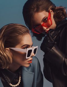 two women with sunglasses on their faces and one wearing a black jacket, the other white