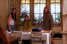 three women standing around a table in a kitchen