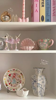 the shelves are filled with china and other decorative items in pink, white, and blue