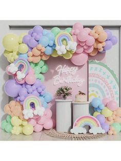 a birthday party with balloons and rainbows on the wall, including an arch that says happy birthday