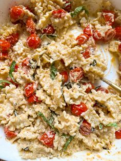 pasta with tomatoes and spinach in a white casserole dish on a wooden table