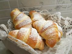 four croissants in a white basket on a doily