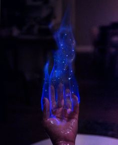 a hand holding something with blue flames coming out of it's palm and fingers