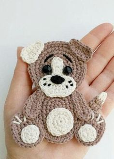 a hand holding a small crocheted teddy bear