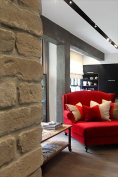 a living room with a red couch and brick wall