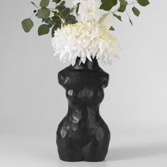 a black vase with white flowers in it