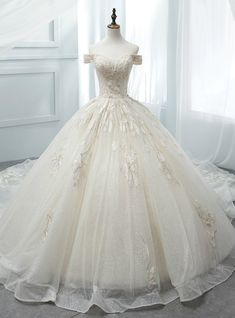 a white wedding dress on a mannequin in front of a curtained window