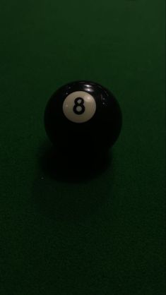 a pool ball sitting on top of a green table with the number eight in it