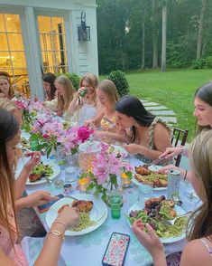 a group of women sitting around a table eating food