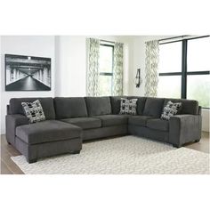 a living room with a large gray sectional couch and white rugs on the floor