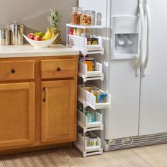 a white refrigerator freezer sitting next to a wooden cabinet in a kitchen with lots of food on top of it