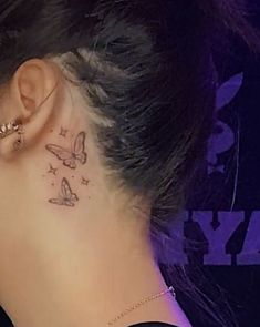 a woman's behind the ear tattoo with butterflies and stars on her left side