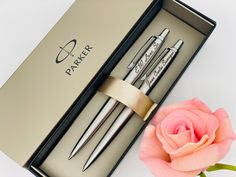 two pens in a gift box next to a rose