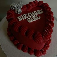 a heart shaped cake with the words birthday girl written on it and two silver hearts