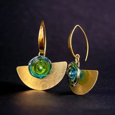 These earrings dangle freely with Lamp work glass in gorgeous shades of translucent green and blue adding a pop of bright color. "Nu Gold" Bronze closely resembles the color of 24K gold and matches the ear wires beautifully which are heavily plated in 24K gold. One of a kind texture is uniquely designed and created by Diana Hirschhorn. Jewelry Details: "Nu Gold" bronze 24K gold plate lamp work glass 1 7/8 x 1 1/2" One-of-a-kind This pair of earrings is available exclusively through the Brenda McMahon Gallery in Gulfport, Florida. Modern Nickel-free Glass Earrings, Green Glass Dangle Earrings, Gold Wire Wrapped Glass Earrings, Green Dangle Glass Earrings, Modern Green Glass Earrings, Modern Green Brass Jewelry, Modern Glass Jewelry With Ear Wire, Modern Glass Earrings With Ear Wire, Modern Gold Glass Earrings