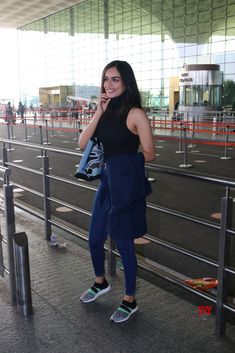 a woman standing in an airport talking on her cell phone