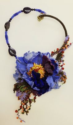 a necklace with beads and flowers hanging from it's side on a white surface