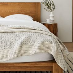 a bed with a white blanket and pillows on it's headboard in a bedroom