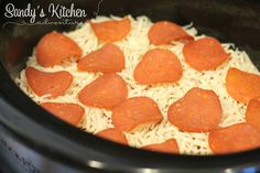 a crock pot filled with cheese and pepperoni pizza toppings, ready to be cooked in the slow cooker