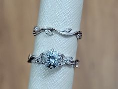 two rings are sitting on top of a white napkin holder, one with an aqua blue diamond