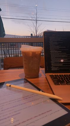 a laptop computer sitting on top of a wooden table next to a cup of coffee