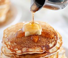 a stack of pancakes with syrup being poured on top