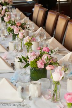 a long table is set with pink and white flowers in vases on each side