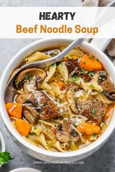 hearty beef noodle soup with carrots and parmesan cheese in a white bowl