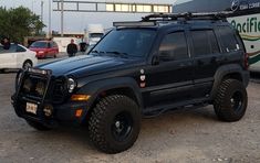 a black jeep parked in front of a bus