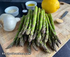 asparagus on a cutting board with garlic and lemon