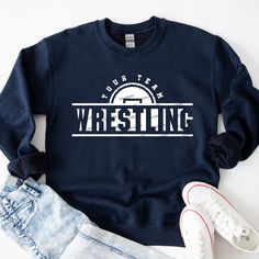 a blue sweatshirt with the words wrestling on it next to ripped jeans and white sneakers