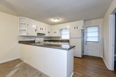 an empty kitchen with white cabinets and black counter tops