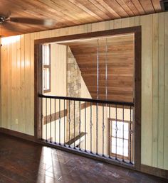 an empty living room with wood paneling and metal railings on the door way