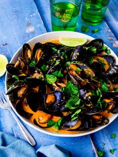 a bowl filled with mussels and garnished with cilantro sauce