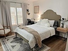 a bedroom with a bed, chair and rug on the hardwood floored flooring