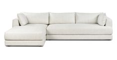 a white sectional couch with pillows on the back and foot rest in front of it