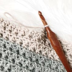 a crocheted blanket with a wooden knitting needle