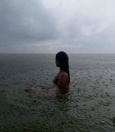 a woman standing in the water with her back to the camera