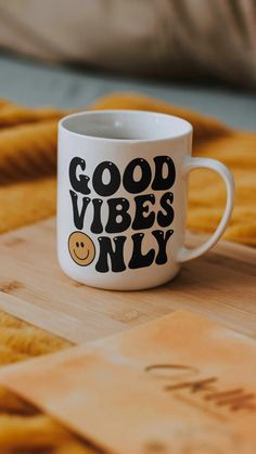 a white coffee mug with the words good vibes only on it sitting on a wooden surface