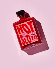 a bottle of hot sauce sitting on top of a white table next to a pink wall