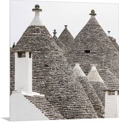 an old stone building with several chimneys and round roof tiles on the top, in front of a cloudy sky