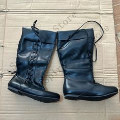 a pair of black boots sitting on top of a cardboard box with laces around them